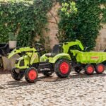 Žalias pedalinis traktorius CLAAS su kaušu, krautuvu ir priekaba