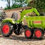 Žalias pedalinis traktorius CLAAS su kaušu, krautuvu ir priekaba