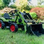 Žalias pedalinis traktorius CLAAS su kaušu, krautuvu ir priekaba