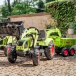 Žalias pedalinis traktorius CLAAS su kaušu, krautuvu ir priekaba